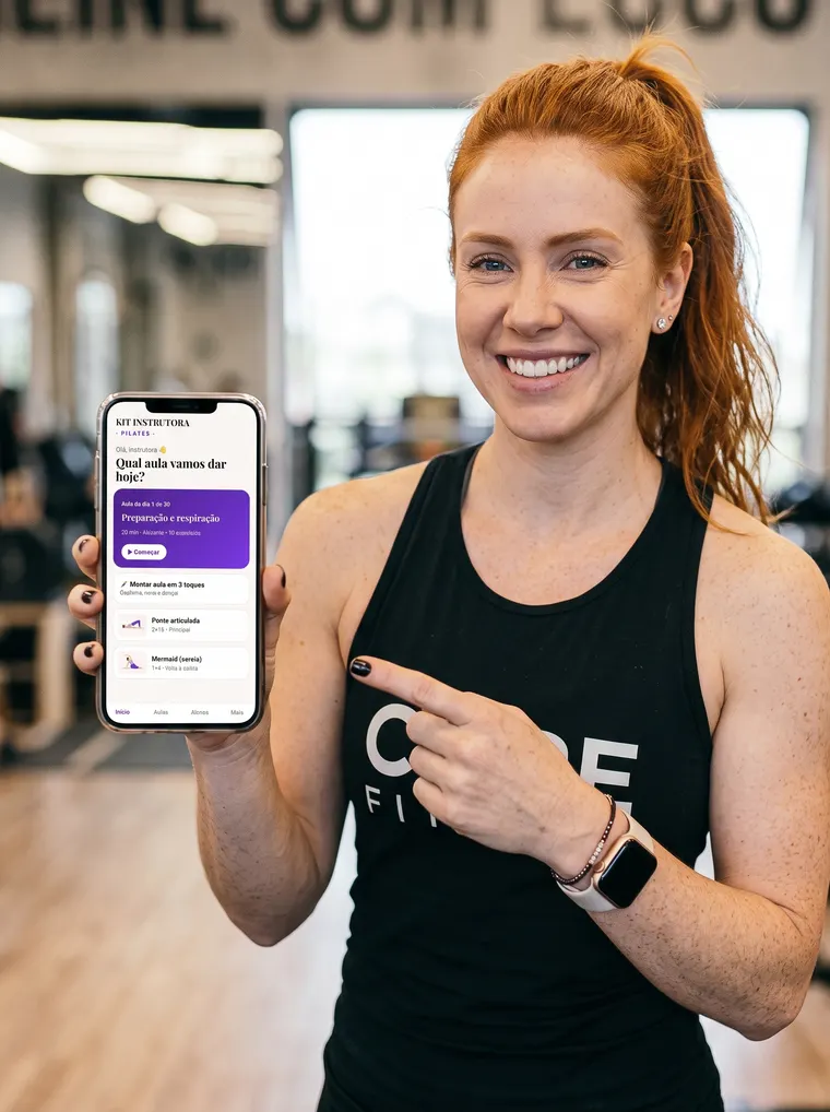 Instrutora de Pilates sorrindo e mostrando o app Kit Instrutora no celular
